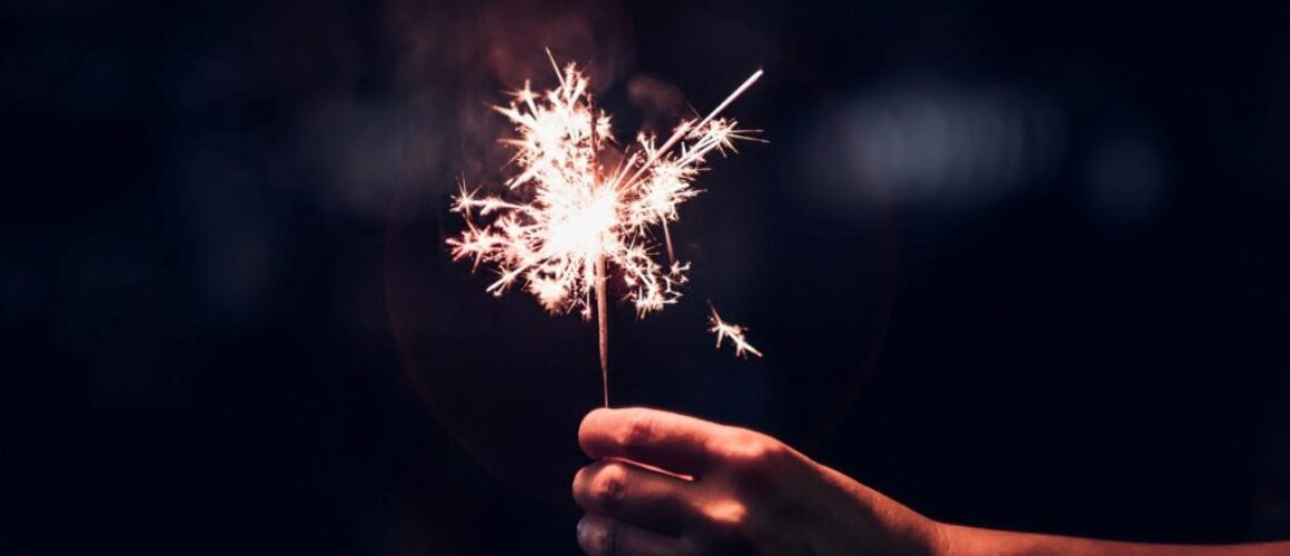 Hand holding burning Sparkler blast on a black background at night