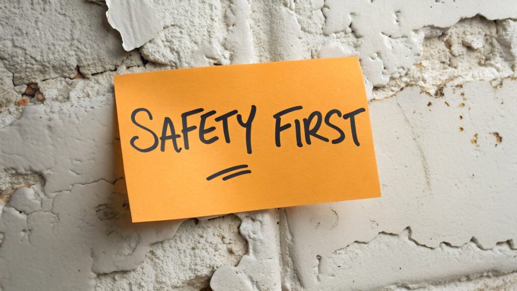 words safety first written on orange sticky note attached to a concrete wall