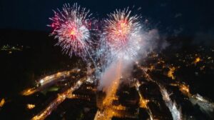 Fireworks Display Over Illuminated Town At Night