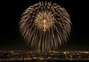 Golden fireworks illuminating the night sky above a sprawling cityscape creating a spectacle of light and color during a festive celebration