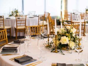 Table at luxury wedding reception event close-up. Beautiful flowers on table and serving dishes and glasses and decoration